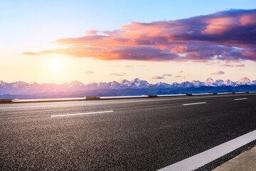 Fototapeta premium Asphalt road and snow mountains with beautiful clouds at sunrise