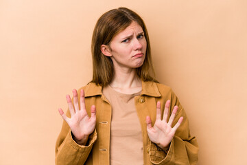 Young English woman isolated on beige background rejecting someone showing a gesture of disgust.