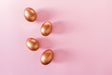 Set of Easter golden color eggs isolated on pastel pink background. Stylish trendy frame composition with gold chocolate egg. Flat lay, top view, place for text. Happy egg hunt for kids concept