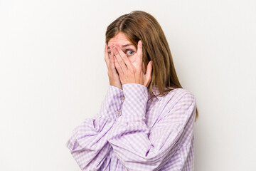 Young russian woman isolated on white background blink through fingers frightened and nervous.