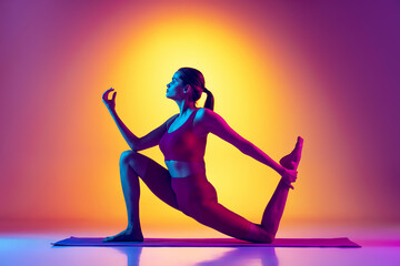 Portrait of young sportive girl training, doing stretching and yoga exercises isolated over gradient pink and yellow background in neon