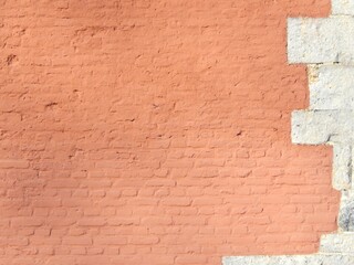 Ancien mur de briques peint en rose avec pierres blanches d'angle