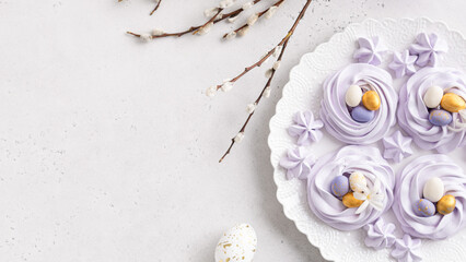 Easter banner, greeting card. Lilac meringue nests with colorful eggs on white background. Bakery, confectionery. Top view, copy space