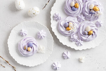 Happy Easter card. Easter meringue nests with eggs candies on the plate on the table with bouquet of willow. Top view, holiday greeting card, confectionery concept. Flat lay. Easter dessert