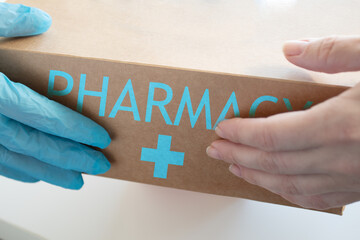 medicines delivery,pharmacist hands the courier a box of pills close up