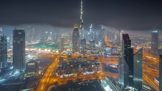 Aerial view of tallest towers in Dubai Downtown skyline and highway all night timelapse.