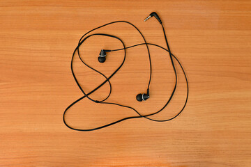 wired headphones tangled in a knot, on a wooden background