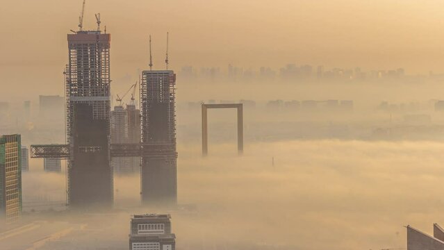 Aerial view of skyscrapers under construction covered by fog in Dubai timelapse.