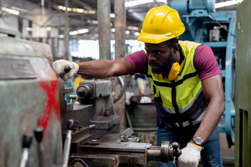 Engineering male african american wear hardhat working at machine in factory. Man technician...