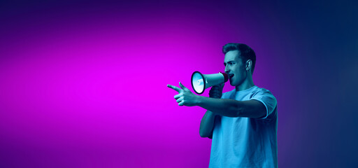 Portrait of young man shouting in megaphone isolated over gradient pink and purple background in blue neon. Flyer