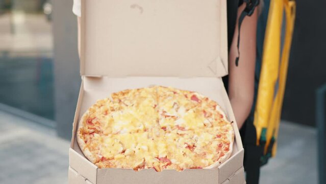 Pizza Delivery. Delivery Woman Wearing Medical Mask and Gloves with Pizza Box Close Up. Delivery Woman stretching out a stack of pizza boxes. Delivery courier offering the pizza in box.