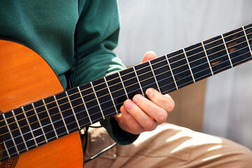 Fototapeta na wymiar Plays the guitar. Guitar strings and fingers. Musical instrument. Man and guitar.