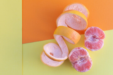A peeled grapefruit on a yellow and orange background