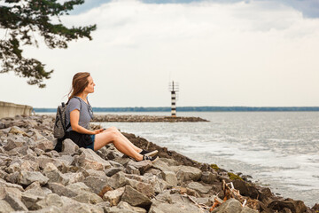 Beautiful girl on the sea overlooking the lighthouse and blue sky with clouds