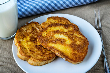 French toast - Przenice - slices of bread soaked in beaten eggs and milk and fried, with a glas of yogurt on a wooden table. Eggy bread, Bombay toast, German toast, gypsy toast or poor knightsles