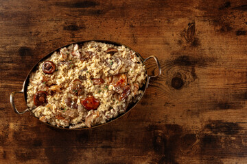 Mushroom risotto, rustic rice with different mushrooms and cheese, shot from the top on a dark wooden background with copy space