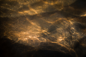 Art of nature - the sun shining through the water in a stream down to the ground