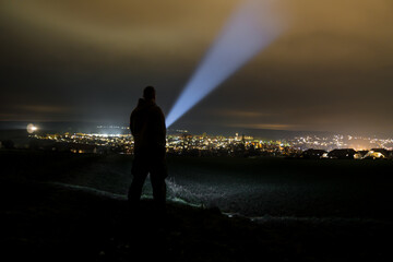 man holding a flashlight and illuminating the sky