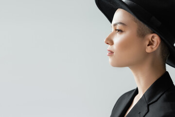 side view of woman in black brim hat isolated on grey with copy space.