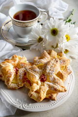 Delicious baked puff pastry with toppings and cup of tea on white background 
