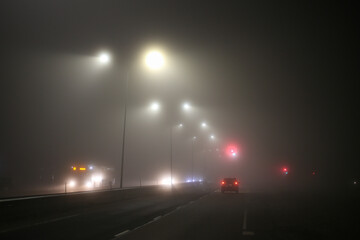 Misty city view of highway with traffic and car lights.