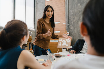 Asia businessmen and businesswomen meeting brainstorming ideas conducting business presentation project colleagues working together plan success strategy enjoy teamwork in small modern office.