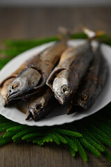 Caught fish, young wild tuna smoked on white plate, vertical view soft focus