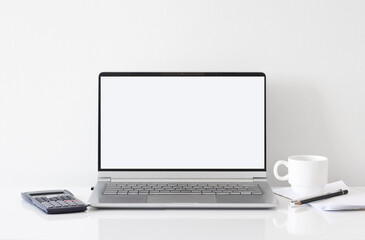 Fototapeta premium Workspace desk, calculator, laptop, coffee cup and pen. Business image, Blank screen computer and supplies. laptop mock up screen view. work from home concept