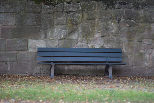 Dark grey bench against a grey wall under the bright sunlight