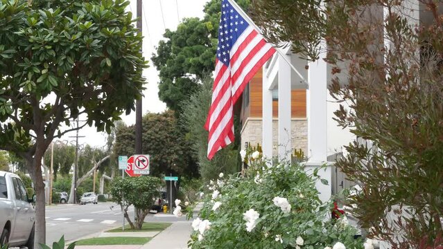 American flag waving on flagpole, suburban house facade, San Diego city street in residential district. Private property, typical building with patriotic symbol. Single-family home architecture in USA