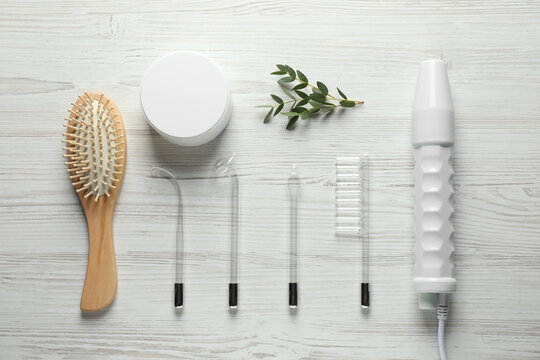 Flat lay composition with darsonval and different nozzles on white wooden table