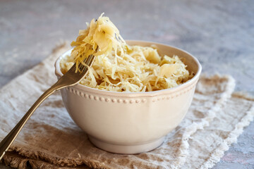 Fermented cabbage or sauerkraut on a fork and in a bowl