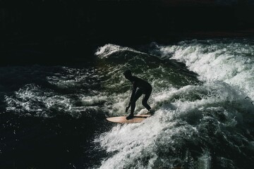 Person surfing in the river in Munich wearing wetsuit