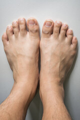 Fototapeta premium The foot and long nail toes on white concrete background. Long n