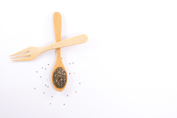 Wooden spoon and wooden fork with plant seeds isolated on white background.