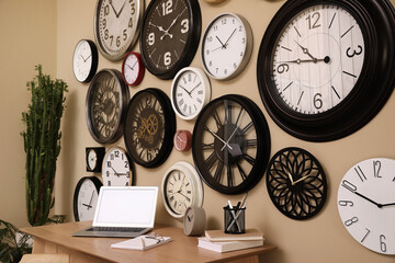 Stylish room interior with collection of wall clocks and workplace