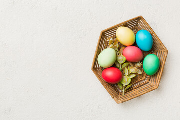 Multi colors Easter eggs in the woven basket on colored background . Pastel color Easter eggs. holiday concept with copy space