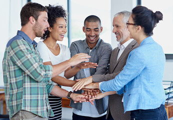 Plakat Pulling together. Shot of a group of happy coworkers standing with their hands together in huddle in an office.