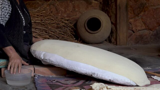 Woman bakes Thin bread lavash (pita) in  tandoor. Flatbread   traditionally baked in  traditional Armenian floor oven called tonir in Western and Central Asia. 