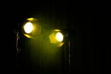 Fototapeta na wymiar Bright yellow spotlights on dark stage, space for text
