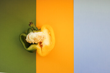 yellow-green half of pepper on a yellow-green-blue background, pepper merging in color with the...