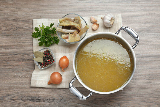 Delicious homemade bone broth and ingredients on white wooden table, flat lay