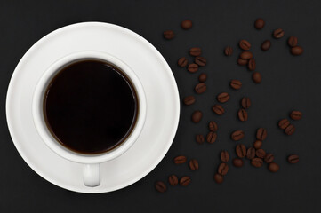 Obraz na płótnie Canvas top view of white ceramic cup hot coffee roasted coffee beans on a dark background 