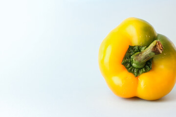 Yellow pepper lies on a light blue surface on the right