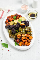 Healthy diet, roasted vegetables on white dish. Top view, flat lay, copy space.