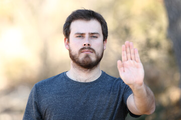 Angry man gesturing stop with hand outdoors