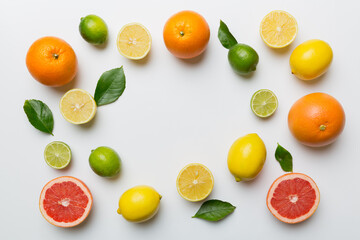 Flat lay of citrus fruits like lime, orange and lemon with lemon tree leaves on light colored background making a frame. Space for text healthy concept