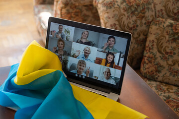 Flag of Ukraine on the background and wide digital screen of laptop with video conference. War with Russia. Cyber attack, sanctions, economic collapse. Message for world peace.