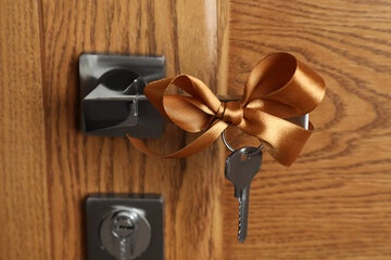 Key with bow on door handle, closeup view. Housewarming party