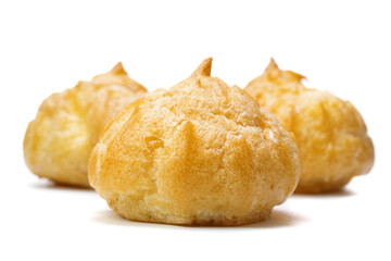 Hollow profiteroles filled with sweet cream isolated on white background, selective focus. Traditional French dessert.